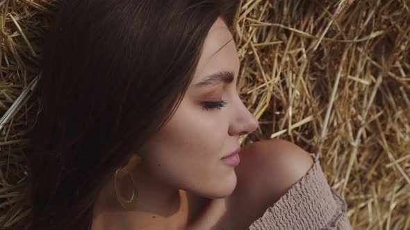 Close Portrait of Brunette Lying on a Hay Opening Eyes and Smiling Into Camera alt