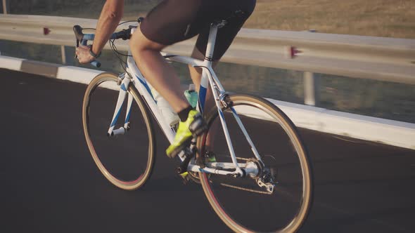 Rear View of a Male Cyclist Riding on the Highway. A Man in a Helmet and Sunglasses, on a Thin alt