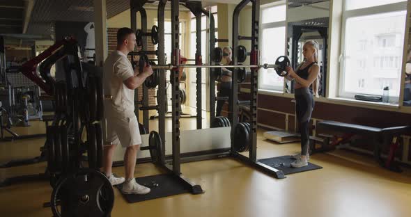 Athletes Attach Dumbbells To The Bar In The Gym