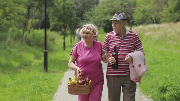 Family Weekend Picnic. Active Senior Old Grandparents Couple in Park. Husband and Wife Walk Together alt