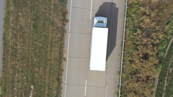 Aerial View of Truck with White Cargo Trailer Driving on Empty Road and Transporting Goods alt