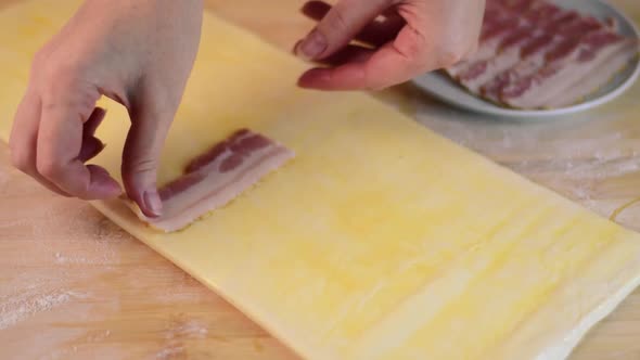 Putting smoked bacon on the sheet of puff pastry alt