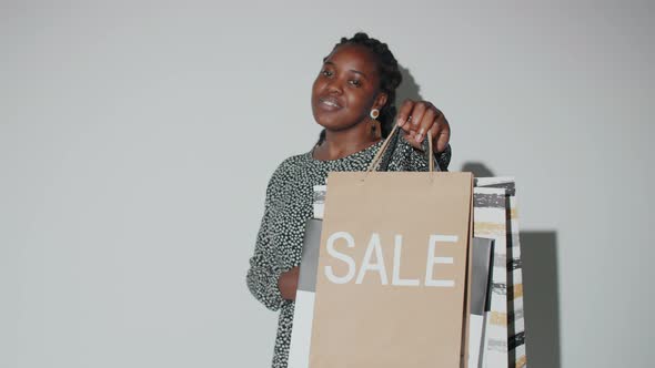 Happy Afro Woman Posing with Sale Shopping Bags alt