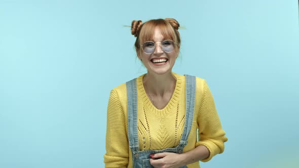 Cheerful Caucasian Woman with Bangs and Funny Buns Haircut Wearing Sunglasses and Sweater Laughing