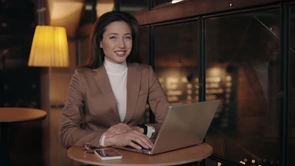 Adorable Woman Using Laptop at Cafe and Smiling at Camera alt
