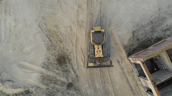 Top Aerial View on Tracked Bulldozer Rides on Sandy Road at Construction Site alt