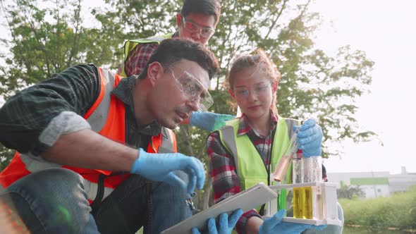 Ecologist leader and assistants check contaminants in factory wastewater in a test tube