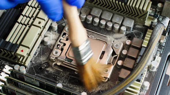 Electronics Technician sweeps dust off computer processor with a special brush