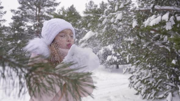 Girl Blow Snow From Palms Throw Snow Up and Turn Around in Forest Winter Snowfall, Show Thumbs Up alt