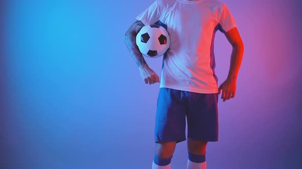 Unrecognizable Football Player Posing Confident with Ball Indoors, Isolated Shot alt