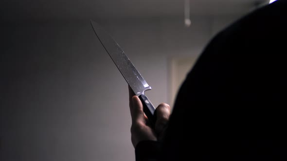 A scary slasher killer holding a terrifying knife in silhouette to attack his murder victim. alt