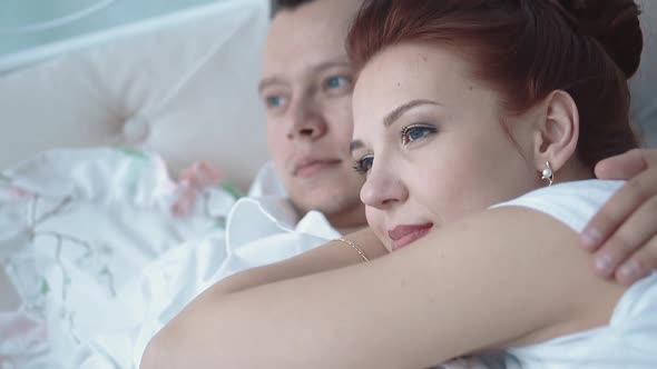 Young Beautiful Couple Resting in Bed Looking Into the Distance Closeup alt
