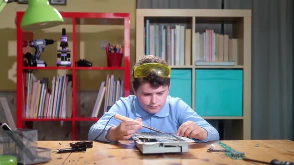 cute schoolboy is studying Electronics and Soldering printed circuit boards