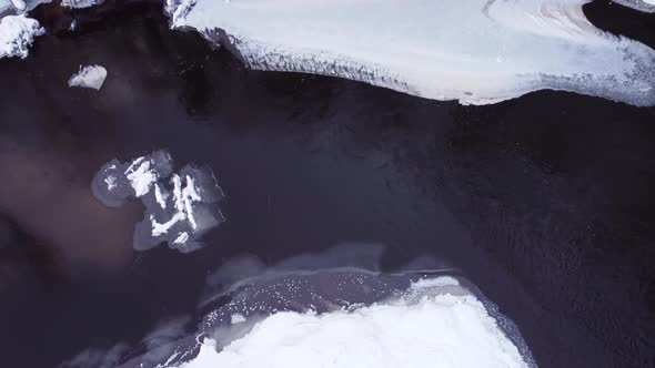 Aerial view of the cliffs and the snow-covered bank of the Brasla River from top to bottom