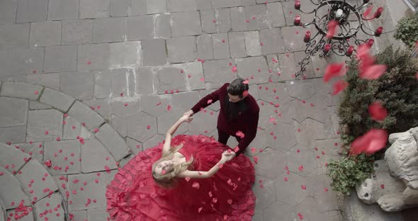 Girl And Guy Stand In Festive Attire And Rose Petals Fly From Above alt