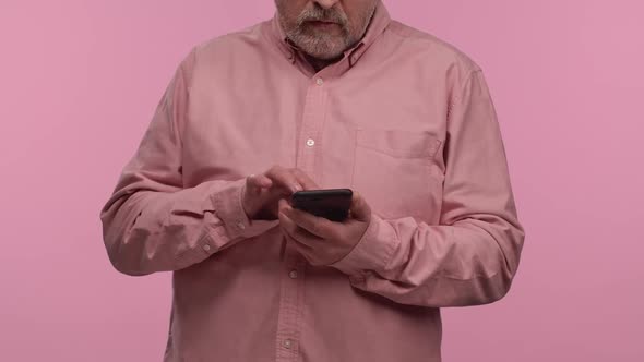 Portrait of an Elderly Man with Glasses Texting on His Phone alt