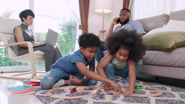 cute little boy and girl African American enjoy toy cars on floor at living room with parent