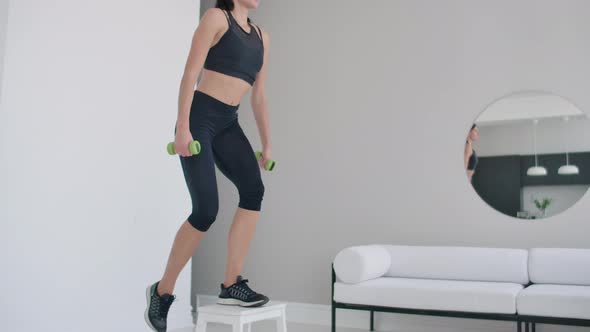 A Young Brunette Woman Performs Concentrated Pacing on a Chair in a Bright Interior Apartment alt