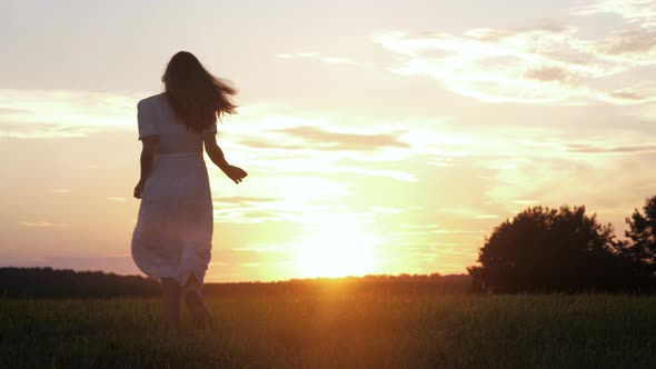 Free Happy Caucasian Woman In White Dress Runs Across Field To Meet The Sunset alt