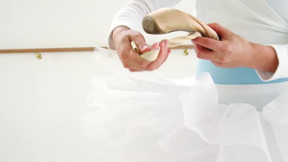 Ballerina holding ballet shoes alt