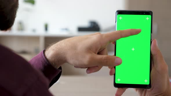 Close Up of Man Hand Touching and Using a Smartphone with Green Screen Chroma Mock Up on It alt