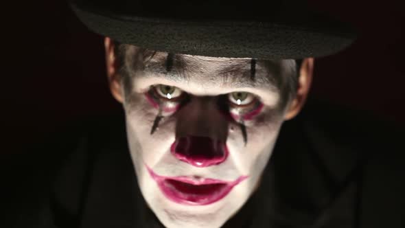 Scary Man in a Clown Makeup Looks at the Camera and Laughs