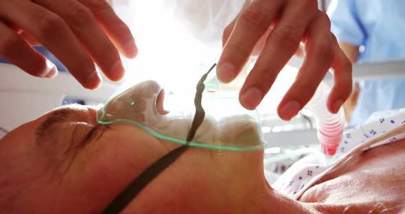 Doctor putting oxygen mask on a female senior patient face alt