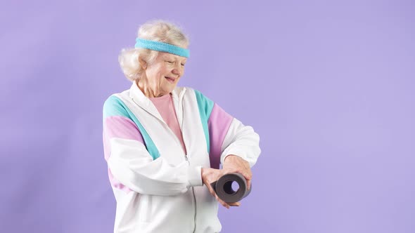 Happy Female Pensioner Holding Yoga Mat in Hands, Comes To Yoga Class in Studio alt