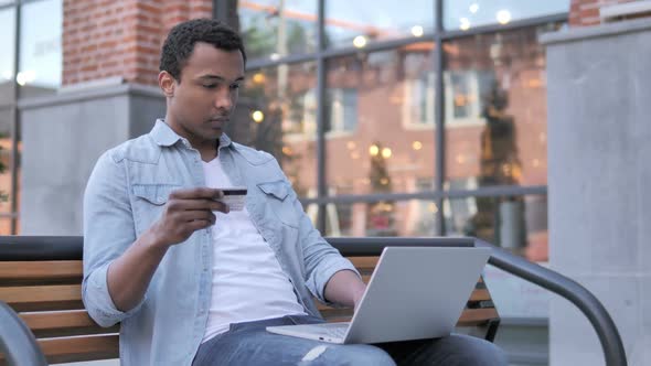 Online Shopping By African Man Sitting on Bench alt