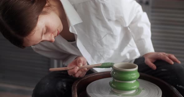 Potter Paints a Jug with a Big Brush on a Potter's Wheel Video From Pottery Workshop Ceramist Makes