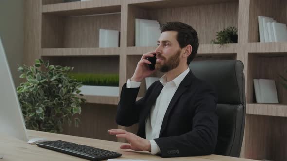 Goodlooking Employee Indoors at His Workplace Talking Positively on the Phone alt