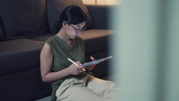 Asian woman reading news on her digital tablet.