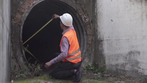 A builder engineer makes measurements of the structure of an underpass under the railway. alt