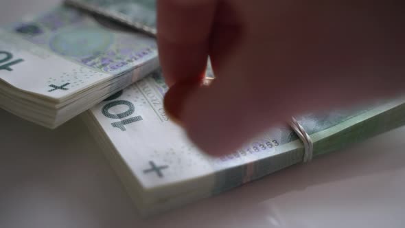 Hand Putting a South African Krugerrand Coin on a Set of Polish Zloty alt