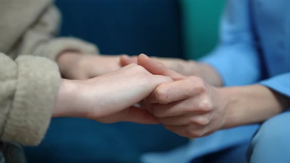 Closeup Caucasian Women Holding Hands Sitting on Sofa Indoors alt