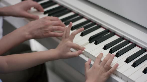 A Close Up Slow Motion Shooting of Hands of an Adult and a Kid Playing Music on the Piano at the