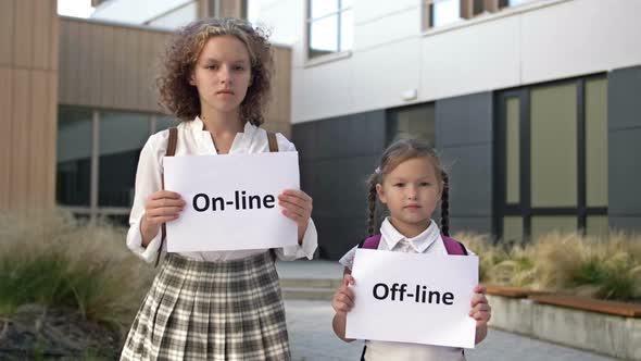 Two Schoolgirls with Placards are Standing in Front of the School Building alt