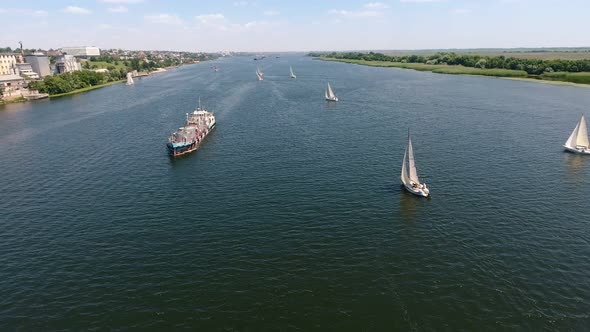 Aerial Shot of Several Yachts and a Big Barge Floating in the Dnipro in Summer 