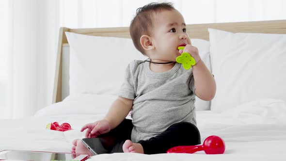 Joyful baby girl paying with toy on the bed
