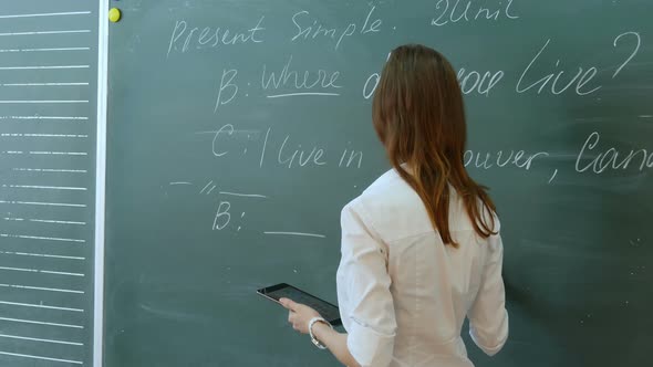 Young Female Teacher in School Classroom Talking To Class on English Lesson alt