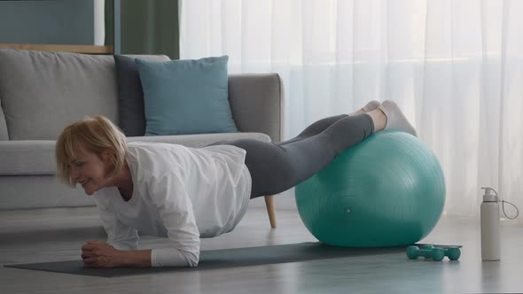 Senior Woman Doing Plank Exercise With Swiss Ball At Home alt