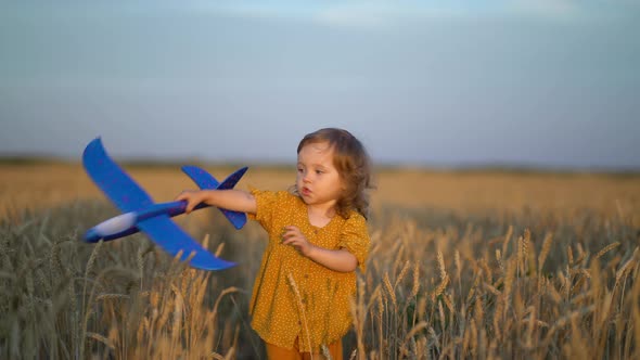 Happy Little Girl Playing with Toy Plane in Wheat Field