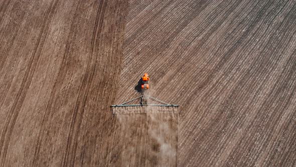 Aerial Footage Modern Red Tractor on the Agricultural Field on Sunny Day. Tractor Plowing Land alt