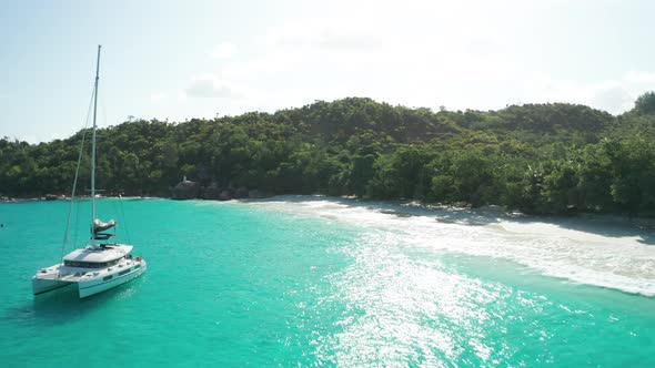 Aerial dolly over emerald water and yacht to Anse Lazio beach, Praslin alt