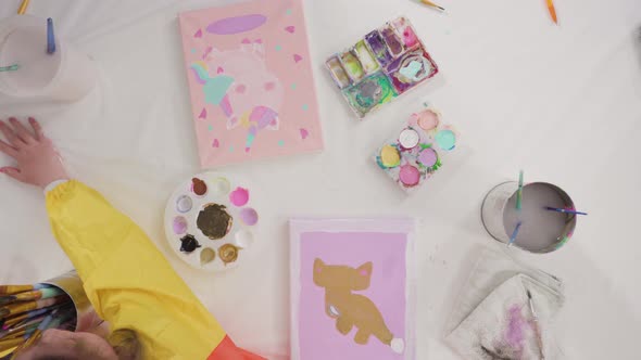 Flat lay. Little girl painting with acrylic paint on canvas with her mother for a distant learning a alt