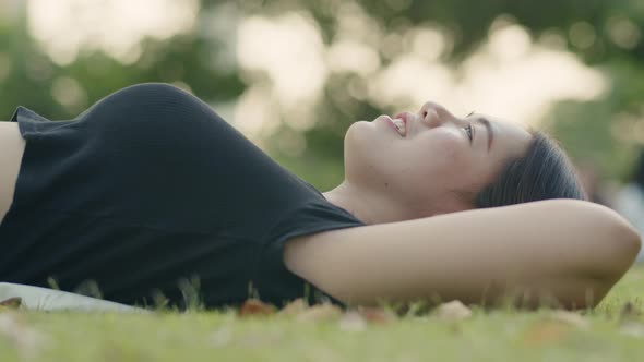 Asian woman while lying on the field green grass.