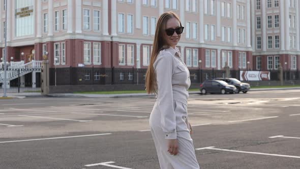 Back View of Funny Smiling Woman in Casual Clothes and Sunglasses Running on the Street Background