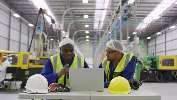 Warehouse workers using laptop in factory alt