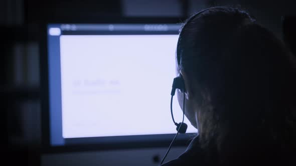 the back of the hacker call center working with computer at night