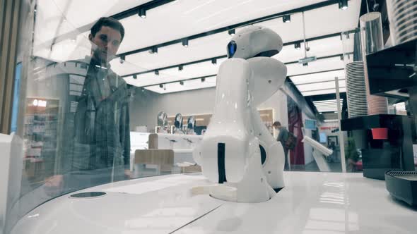 Robotic Machine Is Serving a Man in a Coffee House alt